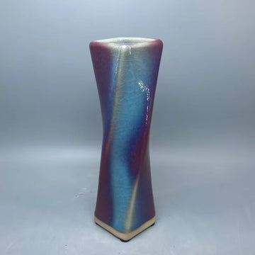 Un vase de céramique aux couleurs irisées et ondulantes, créant un effet visuel élégant et captivant.