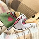 Poupée décorative en tissu avec un motif graphique coloré et whimsique, représentant une créature imaginaire aux traits expressifs.