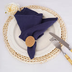 Un élégant réglage de table avec une assiette blanche, des serviettes de table bleu marine, une rose blanche et un support en osier.