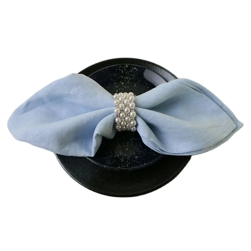 Chapeau noir orné d'un ruban bleu clair avec une rangée de perles.