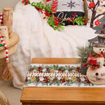 Cette image montre une décoration de Noël colorée et festive, avec des branches d'arbre, des baies rouges, des flocons de neige et un bonhomme de neige en peluche sur une table en bois.