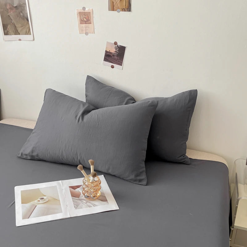 Le lit avec draps gris et coussins, accompagné de polaroids et accessoires décoratifs, crée une ambiance apaisante et élégante dans cette chambre.