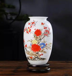Vase en porcelaine décoré de fleurs colorées et de branchages sur fond blanc.