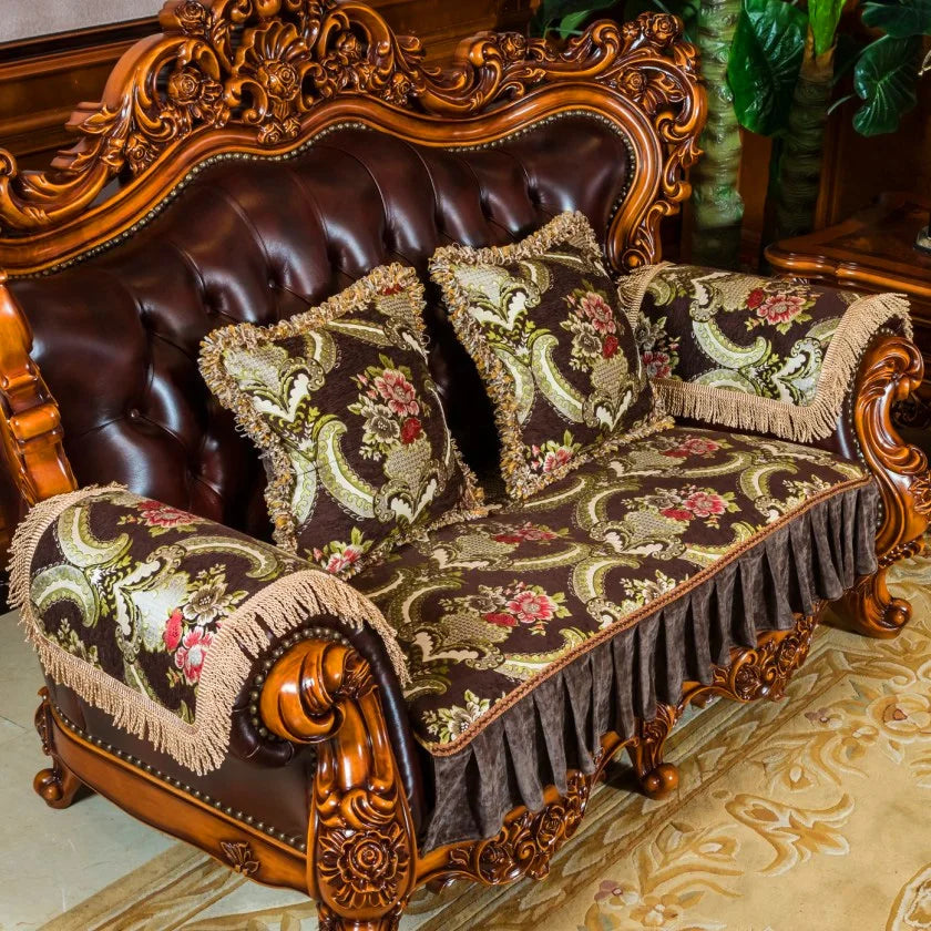 Canapé en cuir luxueux avec des coussins ornés de motifs floraux sur un fond sombre, posé sur un sol recouvert d'un tapis décoratif dans un cadre d'ameublement doré et orné.