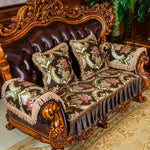 Canapé en cuir luxueux avec des coussins ornés de motifs floraux sur un fond sombre, posé sur un sol recouvert d'un tapis décoratif dans un cadre d'ameublement doré et orné.