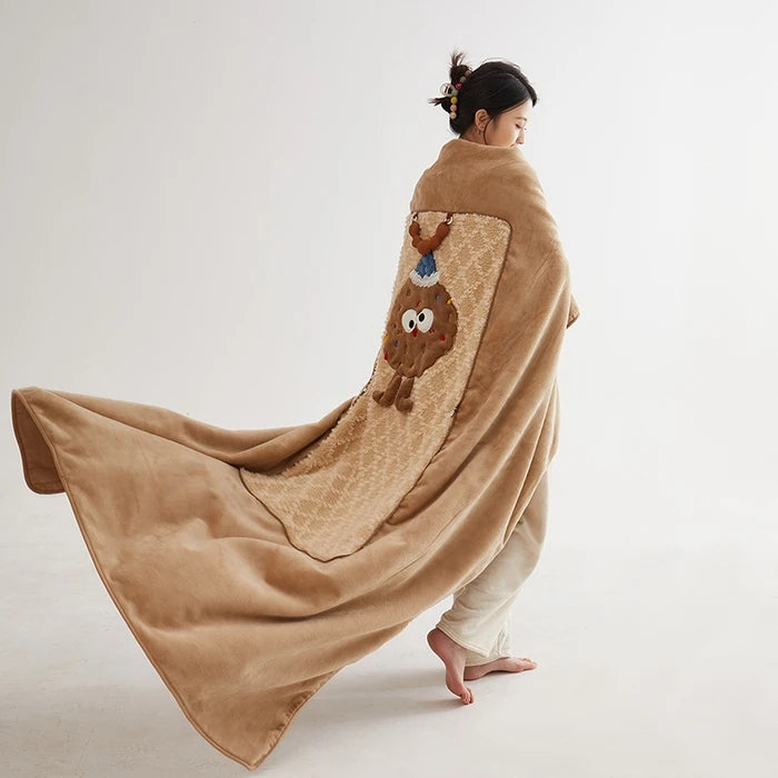 Une personne debout, enveloppée dans une couverture beige à motifs en forme de personnage.