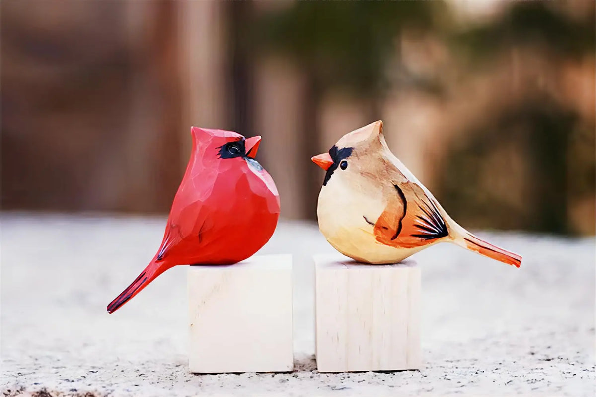 Deux oiseaux colorés, l'un rouge vif et l'autre blanc et brun, perchés sur un support blanc dans un environnement flou.