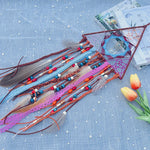 Une composition artisanale colorée de perles, de plumes et de rubans sur fond bleu étoilé.