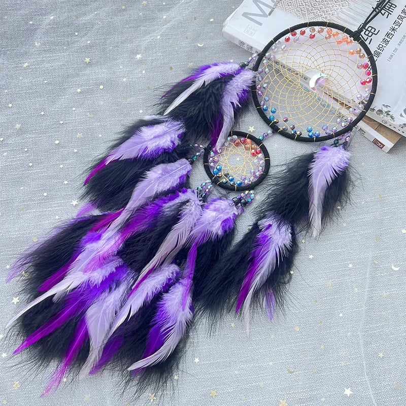 Un attrape-rêve en plumes violettes et noires, avec des motifs colorés, suspendu sur un fond gris brillant.