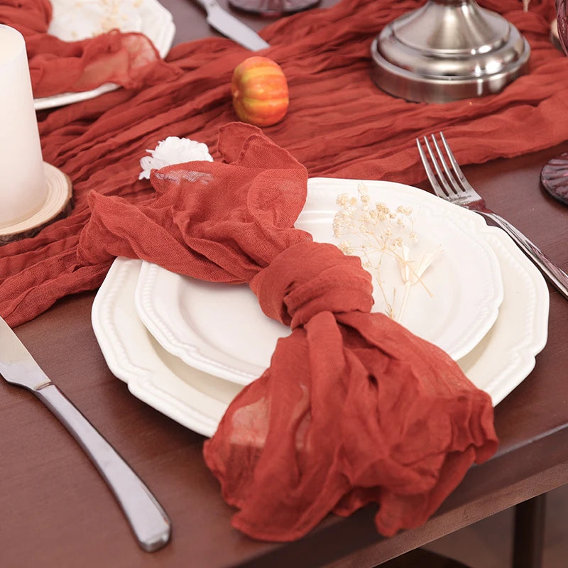 Jolie table de table avec des assiettes blanches, des serviettes rouges et des accessoires dorés, créant une ambiance chaleureuse et automnale.