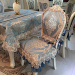 Décor de table élégant avec nappe et chaises ornées de motifs floraux dorés et bleus, créant une atmosphère sophistiquée.
