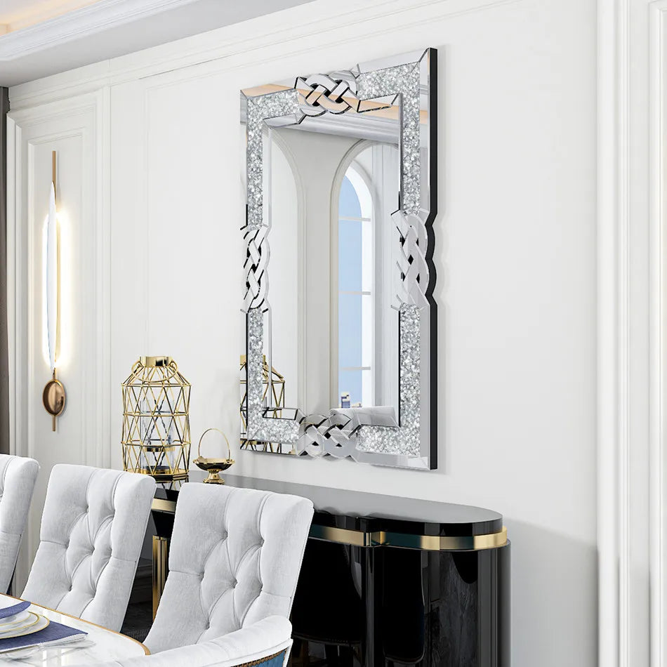 Miroir décoratif brillant avec un motif tressé unique, placé au-dessus d'un console noire et dorée, dans une pièce blanche et lumineuse.
