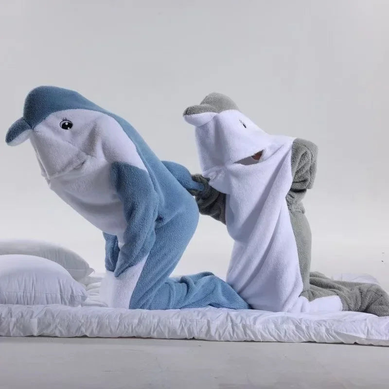 Deux peluches de dauphins bleus et gris reposent sur un lit blanc.