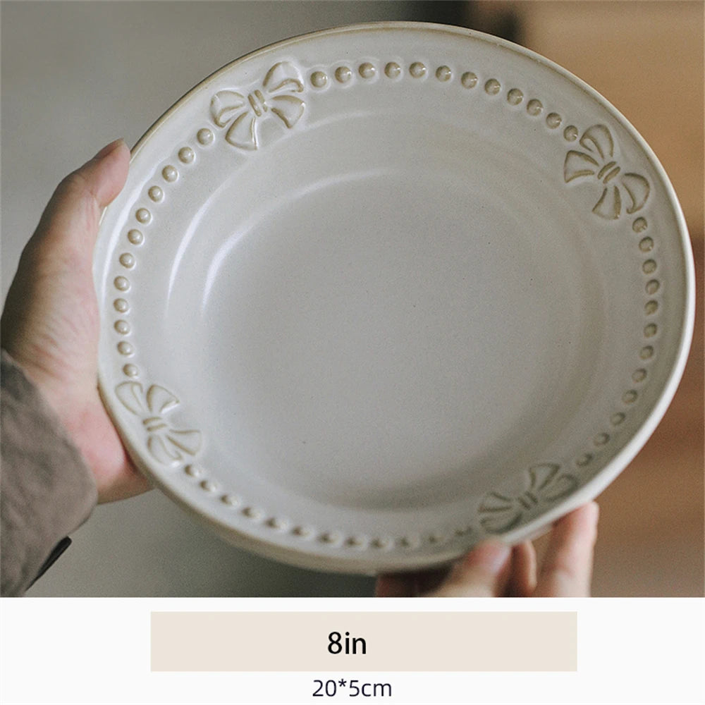 Assiette ronde en céramique blanche avec des motifs floraux décorés sur le bord.