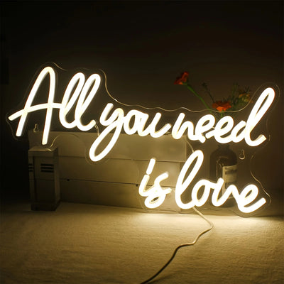 Enseigne au néon LED 'Tout ce dont vous avez besoin est amour' allumée dans une chambre