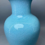 Cette image représente un vase en céramique de couleur bleu ciel avec une texture craquelée.