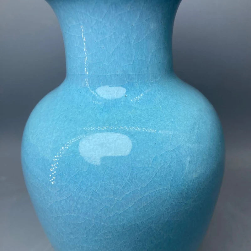 Cette image représente un vase en céramique de couleur bleu ciel avec une texture craquelée.