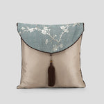 Coussin décoratif de style asiatique avec un motif géométrique et floral sur un fond vert pâle et une bordure beige.