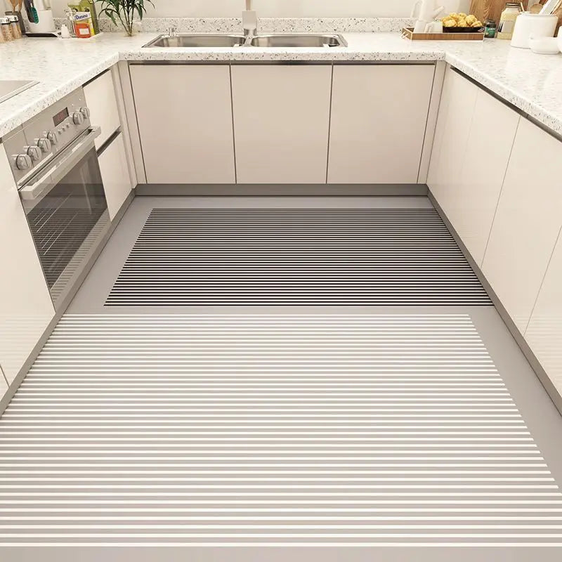 Une cuisine moderne avec des armoires beige et un sol carrelé avec un motif à rayures horizontales en noir et blanc.