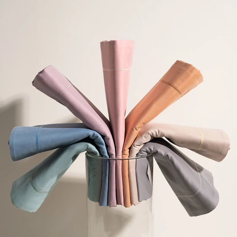 Un assortiment de rouleaux de papier de différentes couleurs, tels que le bleu, le gris, le orange, le rose et le blanc, placés dans un verre transparent.