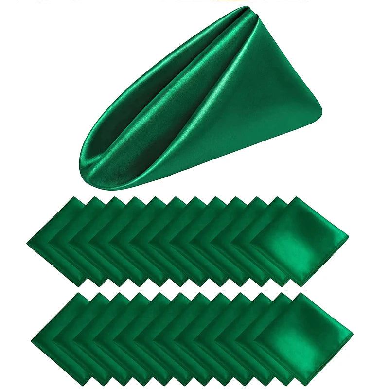 Serviettes de table en satin vert émeraude brillant, pliées de manière décorative et empilées pour créer un motif esthétique.