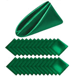 Serviettes de table en satin vert émeraude brillant, pliées de manière décorative et empilées pour créer un motif esthétique.