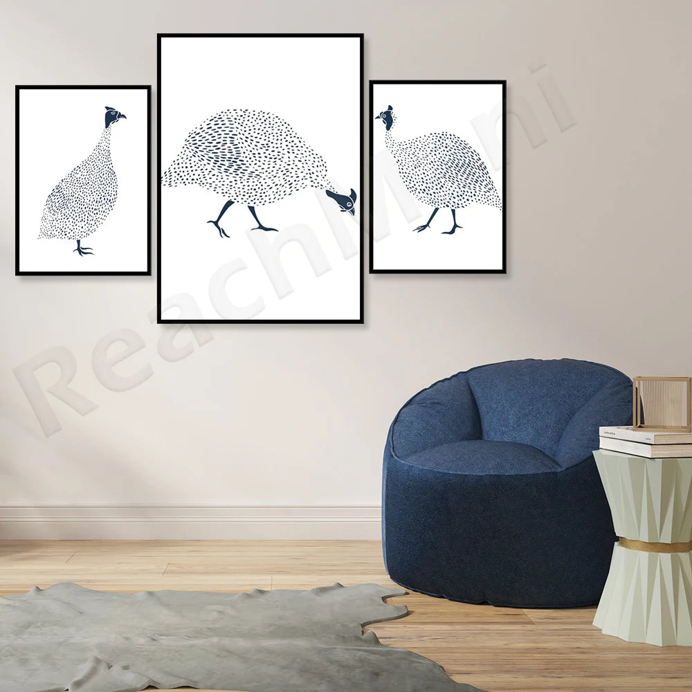 Illustrations de paons en noir et blanc dans des cadres sur un mur blanc, avec un fauteuil bleu foncé et une table basse en bois.