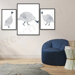 Illustrations de paons en noir et blanc dans des cadres sur un mur blanc, avec un fauteuil bleu foncé et une table basse en bois.