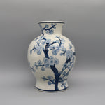 Vase décoratif en porcelaine blanche et bleue avec motif de fleurs de cerisier en fleurs.