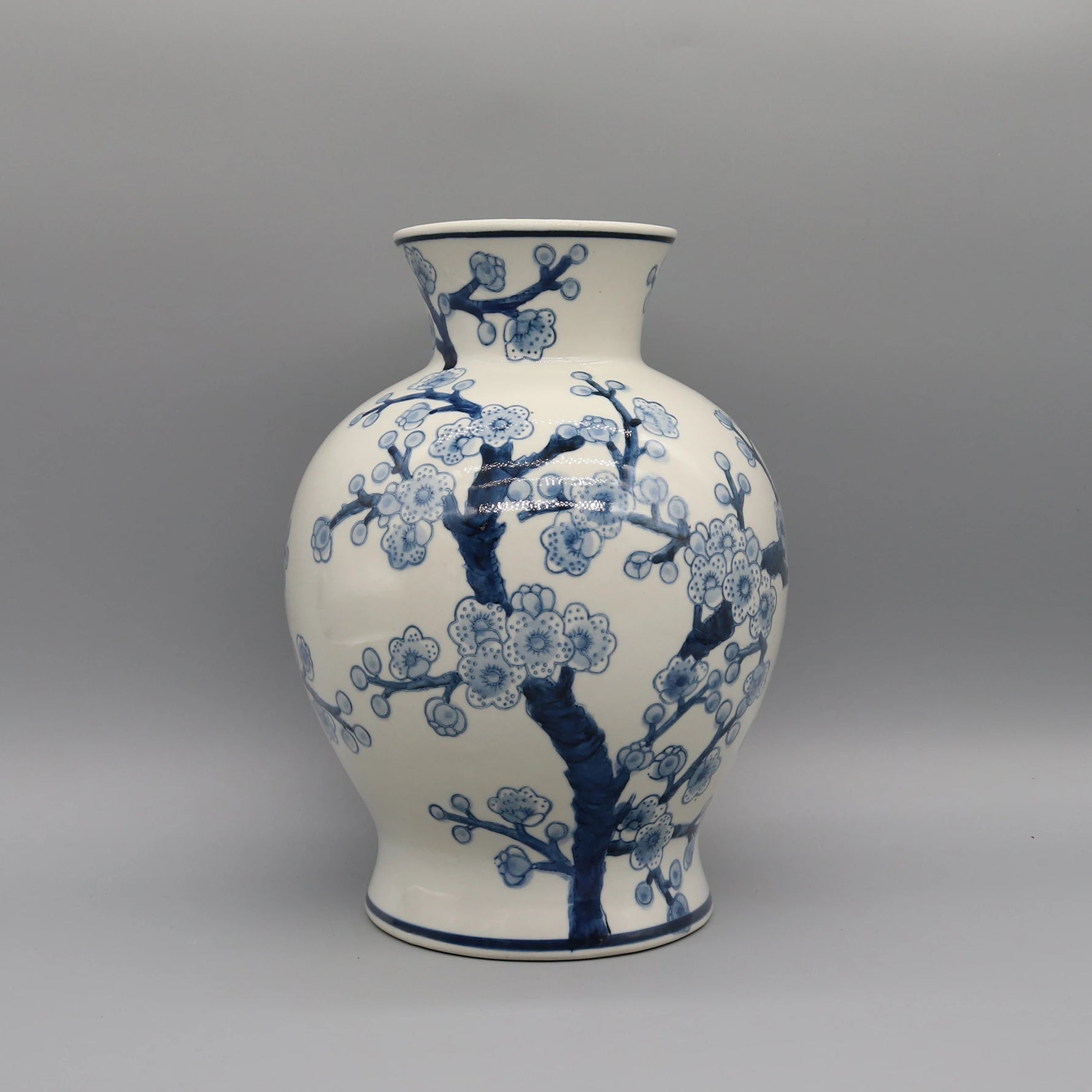 Vase décoratif en porcelaine blanche et bleue avec motif de fleurs de cerisier en fleurs.