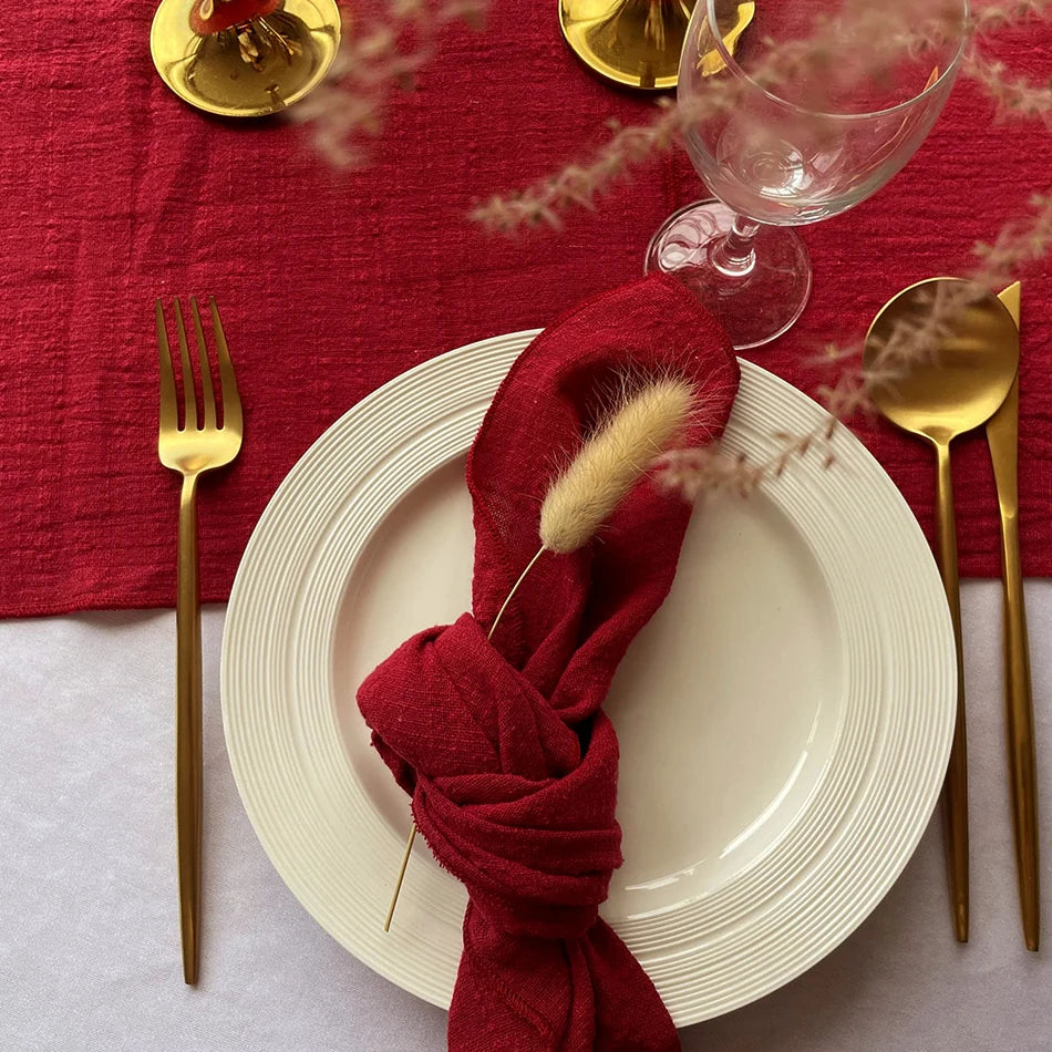 La table élégante dressée dans des tons de rouge et d'or, avec une serviette de table ornée d'un détail en fourrure, crée une ambiance chaleureuse et festive.