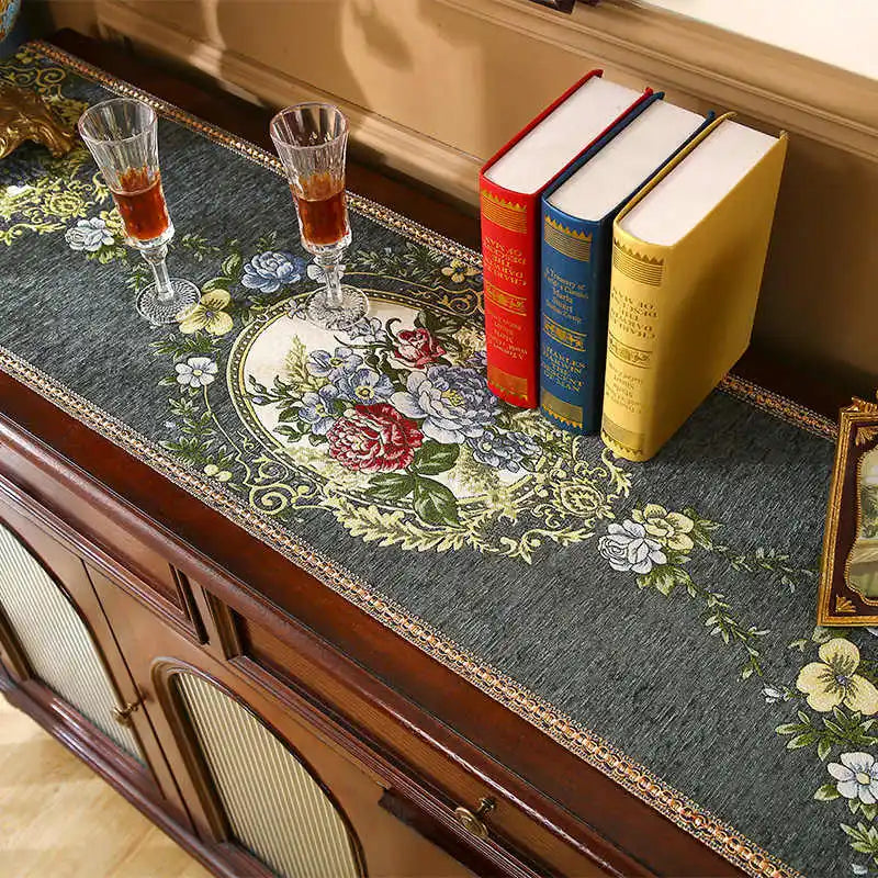 Une élégante table basse ornée de verres de cristal et de livres reliés, sur un fond décoratif floral.