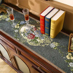 Une élégante table basse ornée de verres de cristal et de livres reliés, sur un fond décoratif floral.