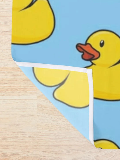 Gros plan du rideau de douche montrant le motif de canard jaune sur fond bleu, ainsi que la bordure blanche du tissu.