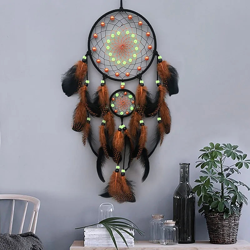 Un fascinant capteur de rêves lumineux aux plumes orange et noires, décorant un intérieur chaleureux avec des accents de verdure.