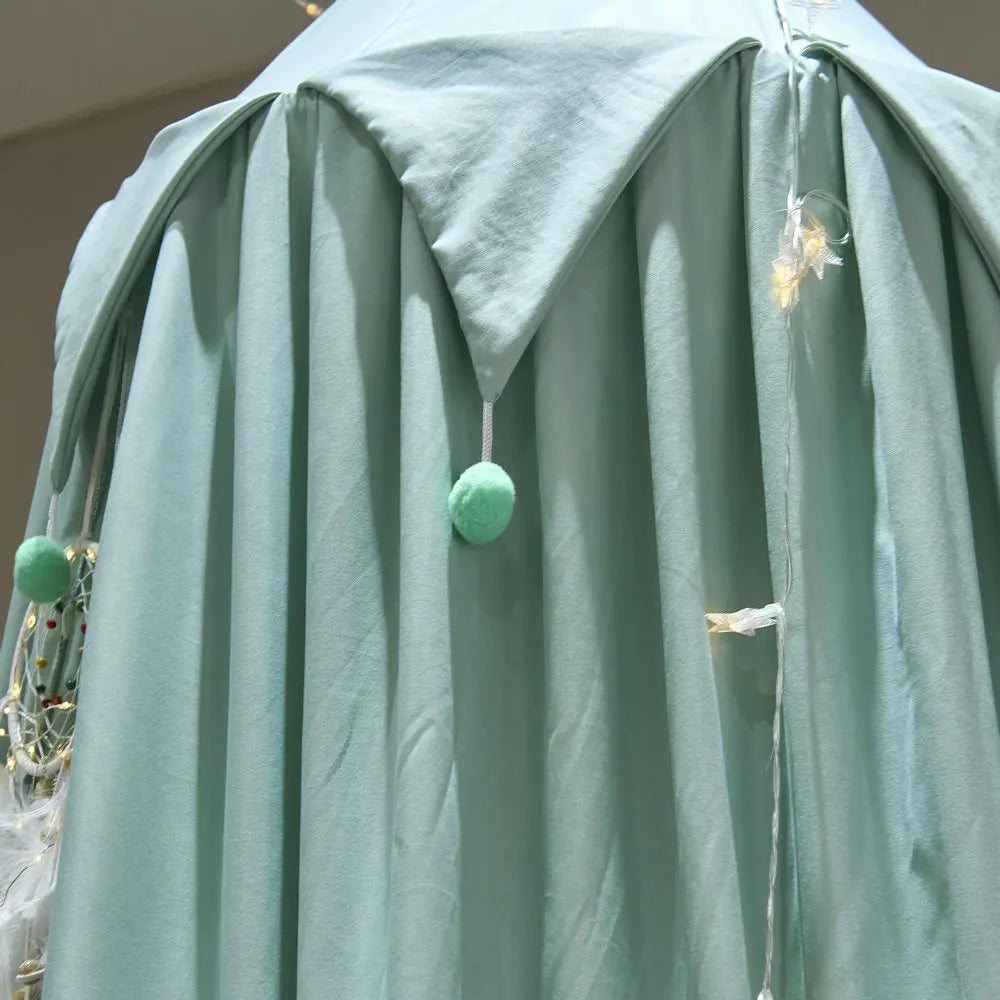 Ample robe de chambre moelleuse en vert pastel, avec des pompons en fourrure verte accrochés.