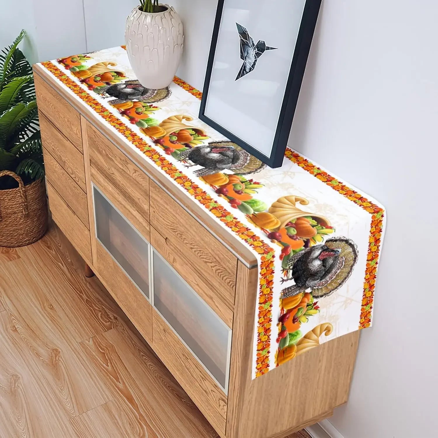 Cette image montre un meuble en bois avec un motif décoratif coloré représentant des fruits et légumes, ainsi qu'un oiseau en origami encadré sur le mur à côté.