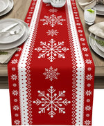 Chemin de table en coton rouge avec motifs blancs de flocons de neige, parfait pour un repas de fête.