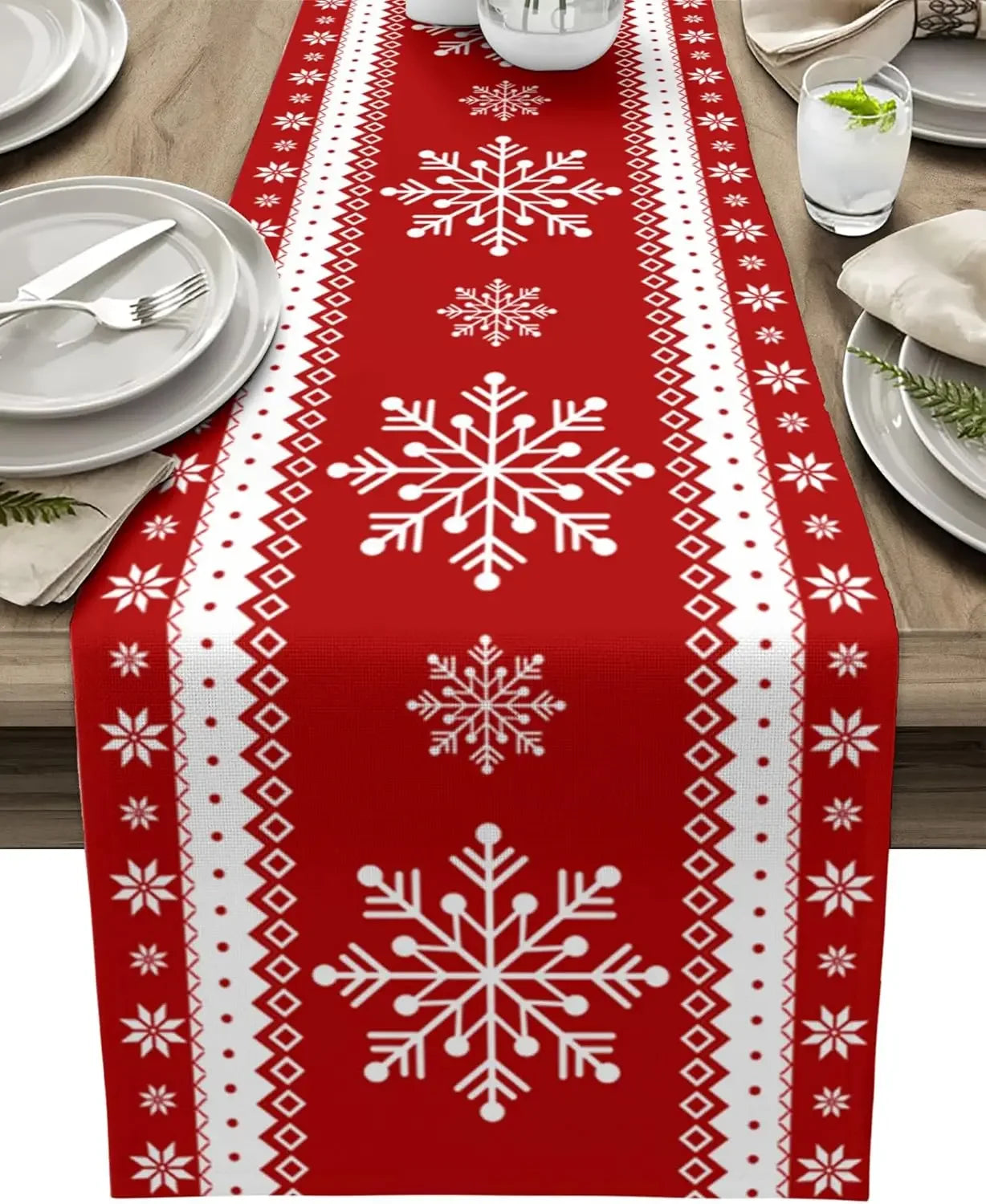 Chemin de table en coton rouge avec motifs blancs de flocons de neige, parfait pour un repas de fête.