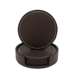 Un ensemble de sous-verres circulaires en cuir de couleur sombre, avec une couture contrastée, posés dans un support en cuir assorti.