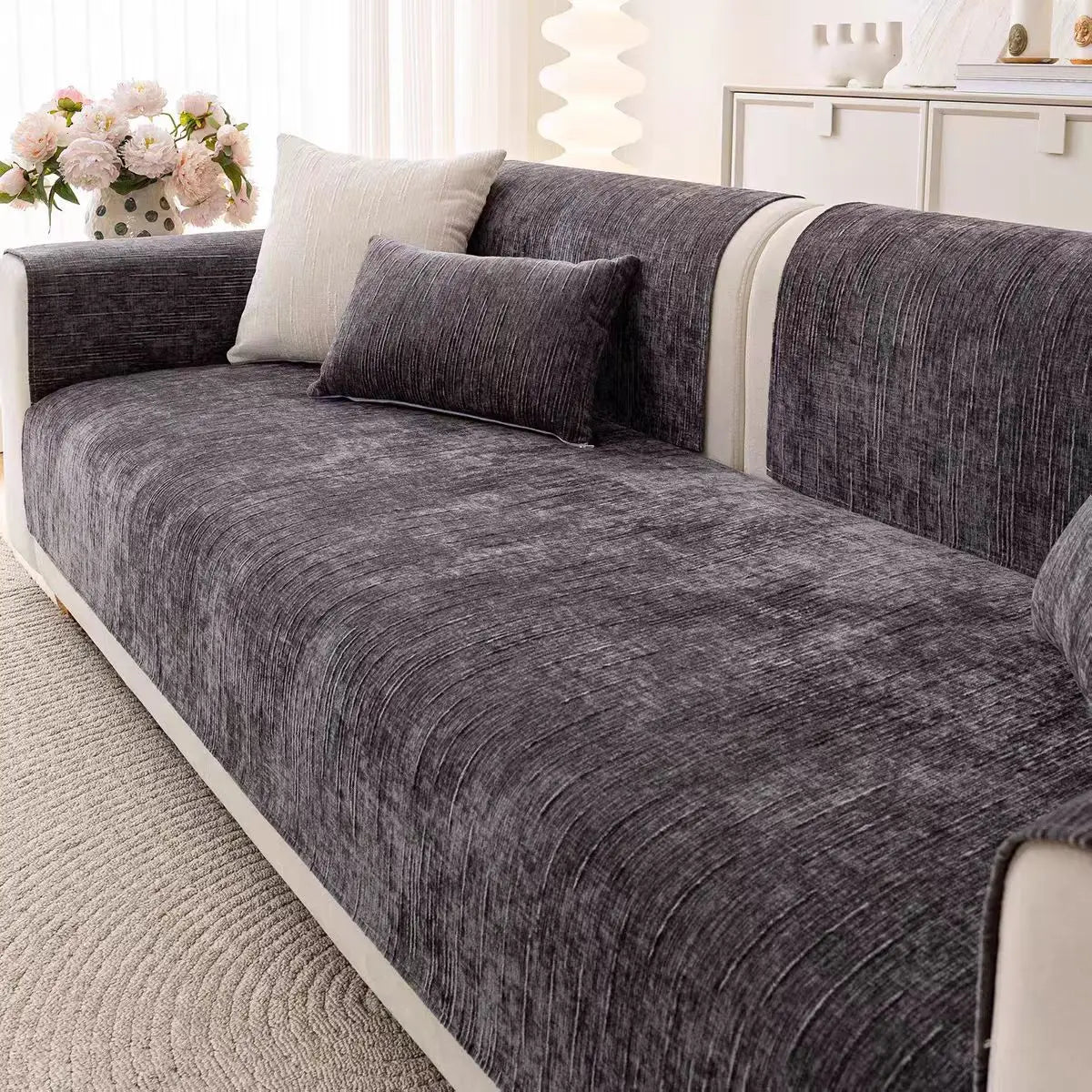 Ce canapé gris aux lignes épurées apporte une touche de sobriété et d'élégance à cet espace de vie lumineux, complété par les fleurs roses qui ajoutent une note de fraîcheur.