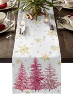 Une table de fête joliment décorée avec une nappe blanche imprimée de flocons de neige dorés et de sapins roses, entourée de verres à vin et de bougies.