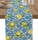 Chemin de table bleu marine avec des citrons jaune vif et des feuilles vertes sur un fond de motifs floraux blancs, créant une atmosphère fraîche et estivale.