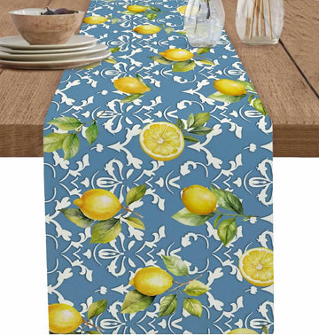Chemin de table bleu marine avec des citrons jaune vif et des feuilles vertes sur un fond de motifs floraux blancs, créant une atmosphère fraîche et estivale.