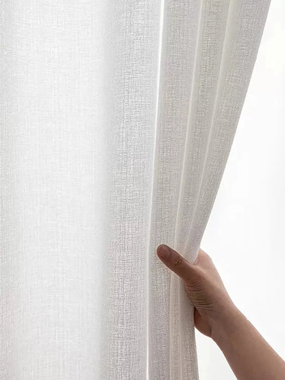 Voilage blanc texturé tenu par une main, en pleine lumière naturelle.