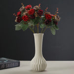 Un magnifique bouquet de roses rouges épanouies dans un vase blanc élégant, rappelant la beauté et l'élégance classique.