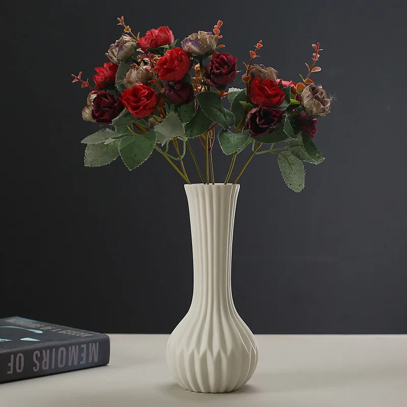 Un magnifique bouquet de roses rouges épanouies dans un vase blanc élégant, rappelant la beauté et l'élégance classique.
