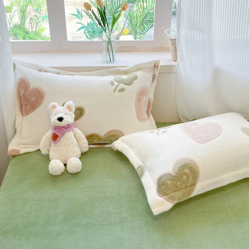 Le couvre-lit et les oreillers sont décorés de motifs de cœurs, créant une ambiance douce et réconfortante dans cette chambre aux tons pastel.