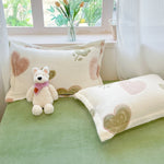 Le couvre-lit et les oreillers sont décorés de motifs de cœurs, créant une ambiance douce et réconfortante dans cette chambre aux tons pastel.