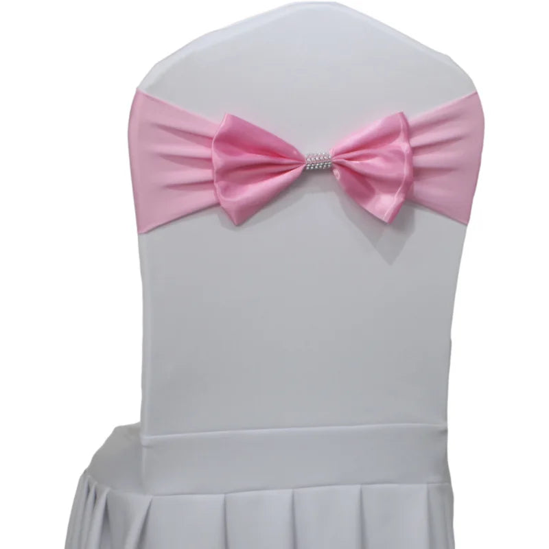 Une housse de chaise blanche dotée d'un nœud papillon rose avec un élément décoratif en strass au centre.